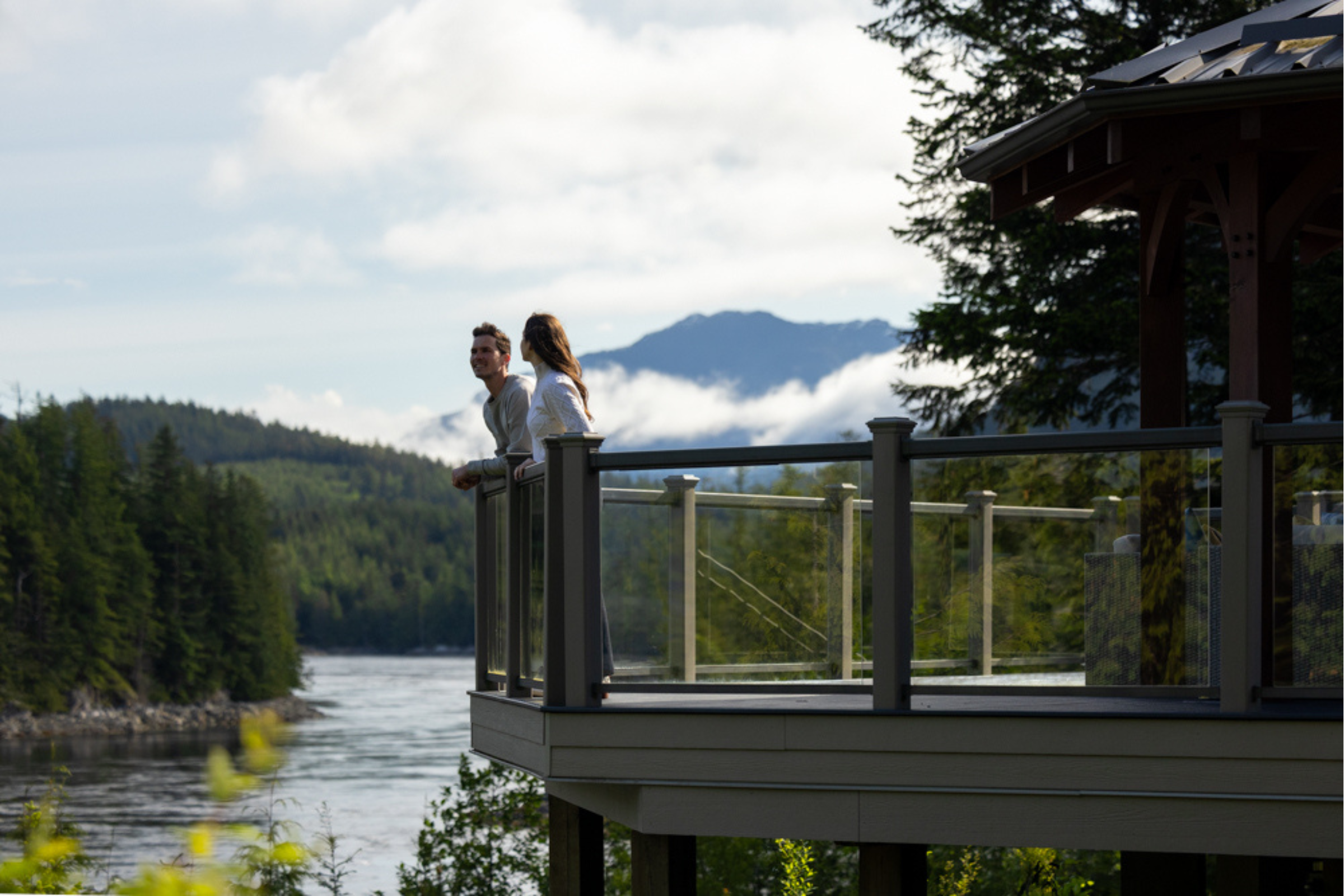 Two people standing on a wooden deck overlooking a scenic landscape with mountains and trees at Sonora Resort.