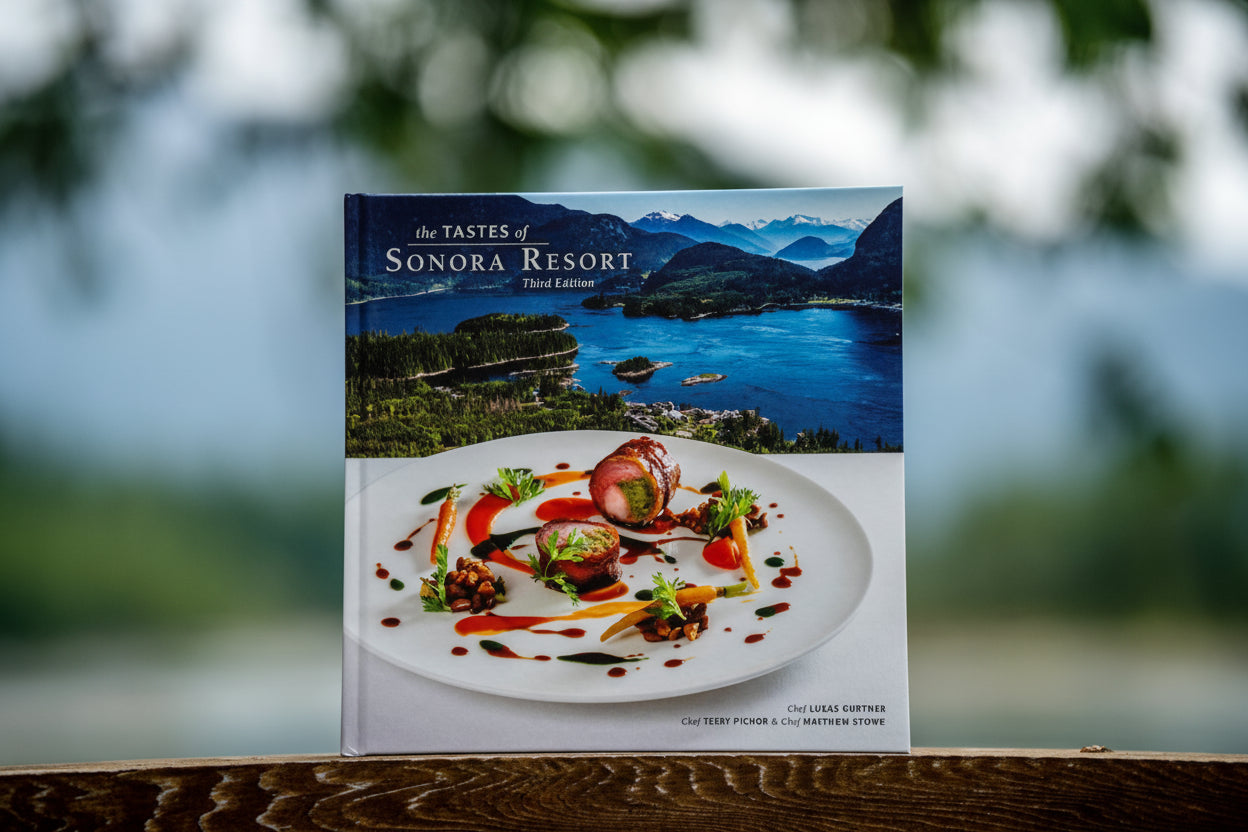 Cookbook, "The Tastes of Sonora Resort," third edition, by Lukas Gurtner sitting on a piece of wood with natural background.
