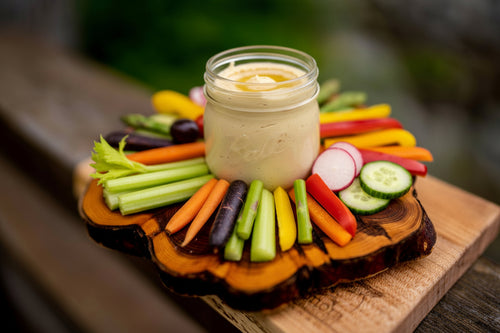 Assorted crudité and olives on a wooden board.