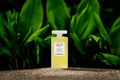 A bottle of Tranquility Oil - bath and body oil - with a dark leafy green background